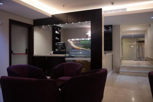 a waiting room with purple chairs and a television at Al JAWHRA TOWER HOTEL in Mecca