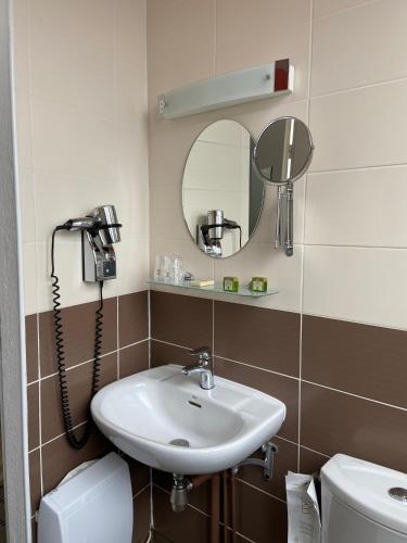 une salle de bain avec un lavabo et un miroir et des toilettes dans l'établissement Hôtel De France - Restaurant L'insolite, à Douarnenez