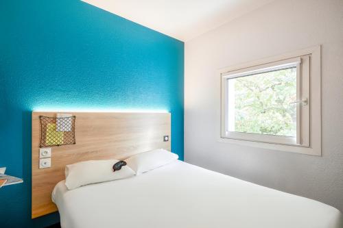 um quarto com uma cama branca e uma janela em HôtelF1 Angoulême em Champniers