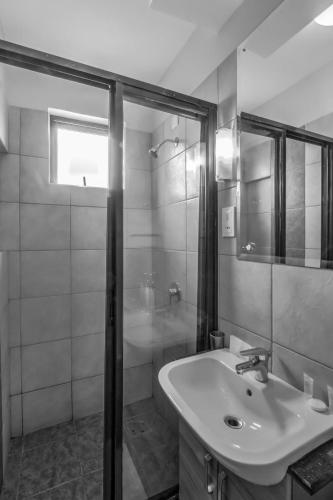 a white bathroom with a sink and a shower at Fedha Residences by Trianum in Nairobi