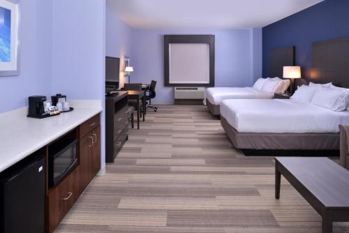 Cette chambre comprend deux lits, un bureau et une table. dans l'établissement Holiday Inn Express Hotels & Suites Loma Linda, an IHG Hotel, à Loma Linda