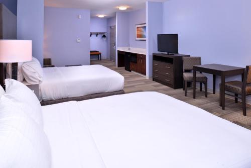 a hotel room with two beds and a desk with a television at Holiday Inn Express Hotels & Suites Loma Linda by IHG in Loma Linda