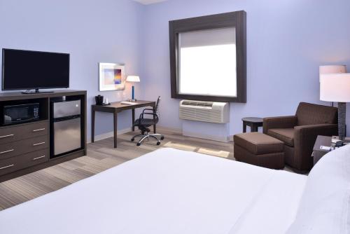 a hotel room with a bed and a tv and a chair at Holiday Inn Express Hotels & Suites Loma Linda by IHG in Loma Linda