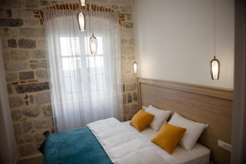 a bedroom with a bed with two pillows and a window at Palazzo Sindik in Kotor