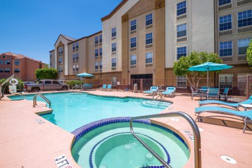 une piscine avec des chaises et des parasols dans un hôtel dans l'établissement Holiday Inn Express Phoenix-Airport/University Drive, an IHG Hotel, à Phoenix