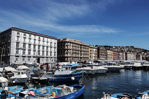 un gruppo di imbarcazioni ormeggiate in un porto con edifici di H Rooms boutique Hotel a Napoli