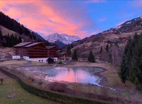 a lodge in the mountains with a lake in the foreground at The River Pearl in Val dʼIlliez