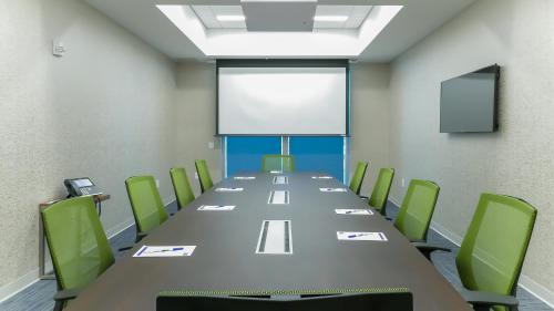 a conference room with a long table and green chairs at Holiday Inn Express & Suites Miami Airport East by IHG in Miami