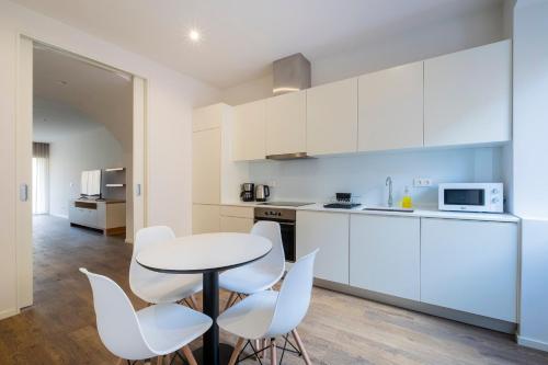 a kitchen with white cabinets and a table and chairs at Casas Amarelas Azores in Ponta Delgada