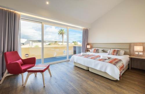 una stanza d'albergo con un letto, una sedia e una finestra di Casas Amarelas Azores a Ponta Delgada