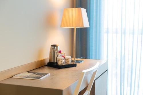 a table with a lamp and a coffee maker on it at Atenea Port Barcelona Mataró in Mataró