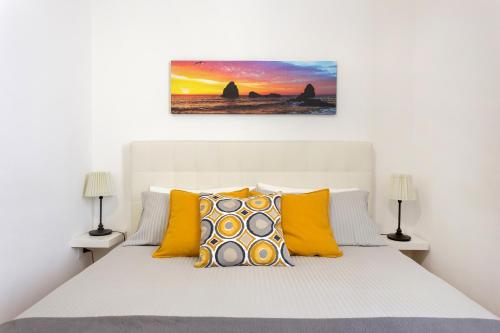 1 dormitorio con cama blanca y almohadas amarillas en Centre Apartment Grotte Bianche en Catania