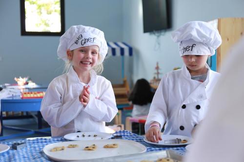 two young girls wearing chefs hats standing at a table at Kenzi Club Agdal Medina - All Inclusive in Marrakesh