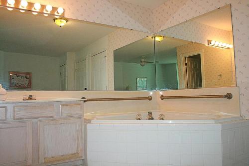 een badkamer met een bad en een grote spiegel bij Brunswick Plantation Golf Home 501L in Calabash