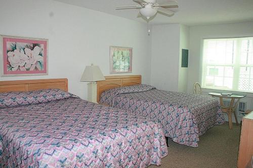 Cette chambre comprend deux lits et un ventilateur de plafond. dans l'établissement Brunswick Plantation Golf Home 501L, à Calabash