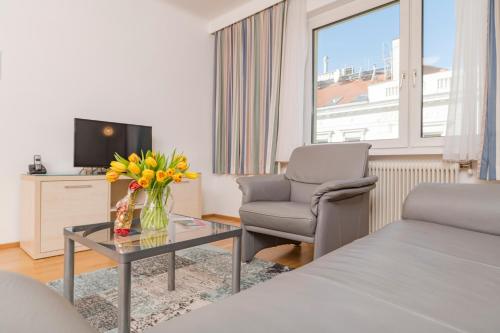 een woonkamer met een bed en een tafel met bloemen bij Appartements Ferchergasse in Wenen