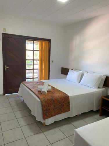 Un dormitorio con una gran cama blanca y una ventana en Hotel Monte Pascoal Smart en Porto Seguro