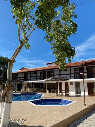 a building with a swimming pool and a tree at Rede Andrade Estrela Dalva Praia Hotel in Porto Seguro