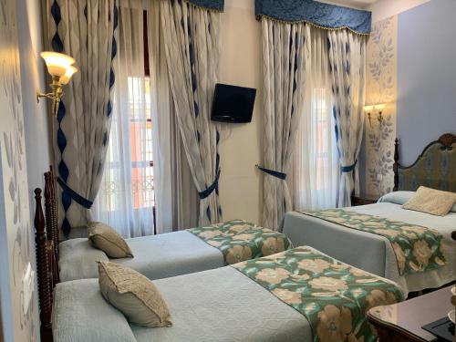 a hotel room with two beds and a television at Hotel Europa Boutique Sevilla in Seville