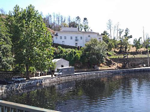 una casa blanca sentada junto a un cuerpo de agua en Casa das Relvas, en Penalva de Alva