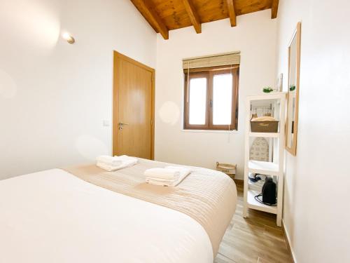 a white bedroom with a bed and a window at Casa do Sapateiro - No centro histórico de Aljezur in Aljezur