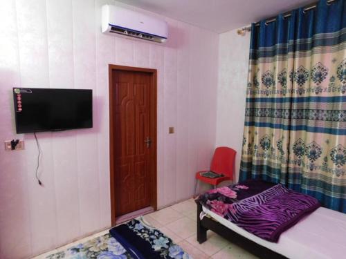 Shah Taj Hotel في لاهور: غرفة نوم بسرير وتلفزيون بشاشة مسطحة
