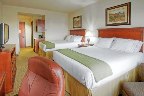 a hotel room with two beds and a chair at Holiday Inn Express Hotel & Suites Las Cruces by IHG in Las Cruces