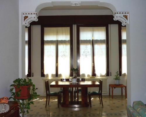 a dining room with a table and chairs and windows at Il Giardino Segreto in Imola