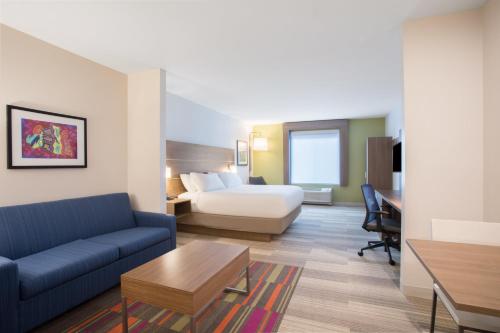 a hotel room with a couch and a bed and a desk at Holiday Inn Express & Suites Owings Mills-Baltimore Area by IHG in Owings Mills