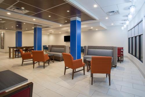 a waiting room with chairs and tables and a tv at Holiday Inn Express & Suites Owings Mills-Baltimore Area by IHG in Owings Mills