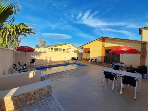 a patio with tables and umbrellas next to a pool at Caseta De L'avi in Camarles