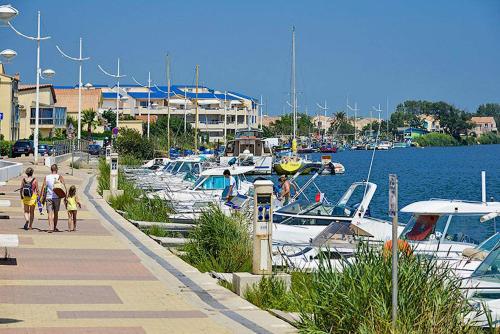 un grupo de personas caminando por un muelle con barcos en Le Chalet, en Valras-Plage