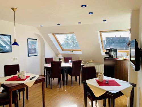 a dining room with tables and chairs and windows at Aparthotel Kleine Perle in Cuxhaven