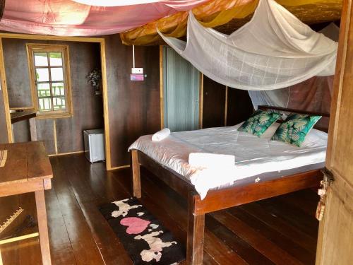 a bedroom with a bed with a mosquito net at Beachfront Hut Downstairs Astra - Beach Shack Chalet in Tioman Island