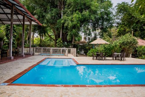 a swimming pool with a table and chairs and an umbrella at Hotel Restaurante Selva Negra in Turbaco