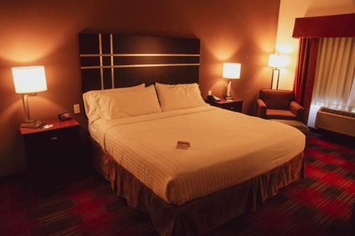 a hotel room with a large bed and a chair at Holiday Inn Express & Suites Cumberland - La Vale by IHG in La Vale