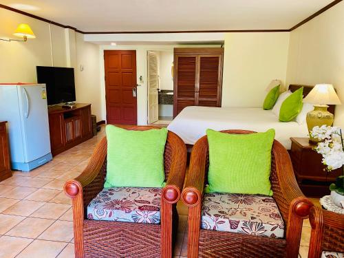 1 dormitorio con 1 cama y 2 sillas de mimbre en Surin Bay Inn en Surin Beach