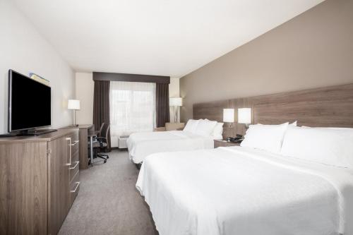 a hotel room with two beds and a flat screen tv at Holiday Inn Express & Suites Manhattan by IHG in Manhattan