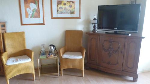 a living room with two chairs and a flat screen tv at Hotel Landhaus Lahmann in Bad Eilsen