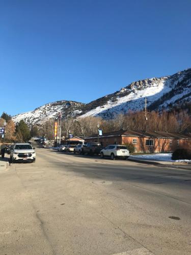a street with cars parked in front of a snow covered mountain at Lava Spa Motel & RV in Lava Hot Springs