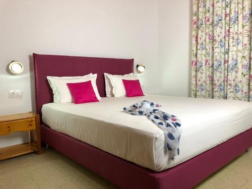 a bedroom with a large bed with pink and white pillows at Laios Hotel (Adults Only) in Limenas