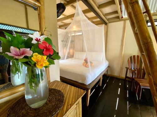 a bed with a vase filled with flowers on top of it at Little Corn Island Beach and Bungalow in Little Corn Island