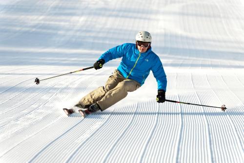 a man is skiing down a snow covered slope at The Black Bear Lodge at Stratton Mountain Resort in Stratton Mountain