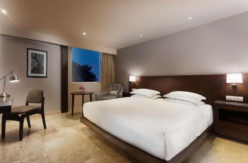 a bedroom with a large white bed and a desk at Hyatt Regency Villahermosa in Villahermosa