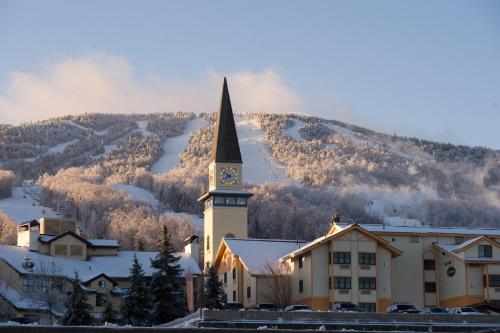 a church with a clock tower in front of a mountain at The Black Bear Lodge at Stratton Mountain Resort in Stratton Mountain
