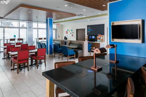 a restaurant with tables and chairs and a tv at Holiday Inn Express & Suites - Medford by IHG in Medford