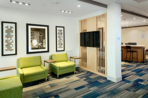 a waiting room with green chairs and a flat screen tv at Holiday Inn Express & Suites - Medford by IHG in Medford