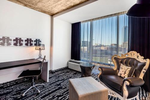 a hotel room with a chair and a desk and a window at Lorenzo Hotel Dallas, Tapestry Collection by Hilton in Dallas