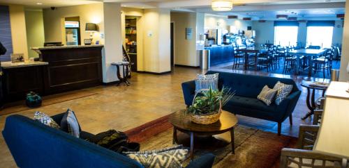 a lobby with blue couches and tables and a restaurant at Holiday Inn Express & Suites Malone, an IHG Hotel in Malone