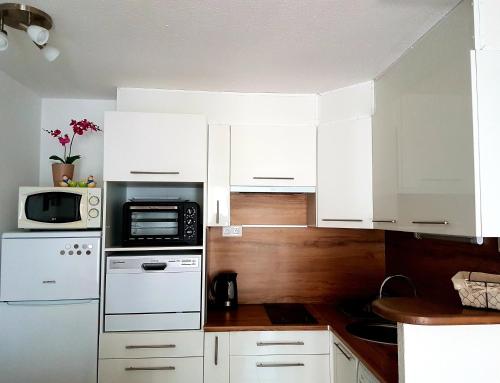 eine Küche mit weißen Schränken und einer Mikrowelle in der Unterkunft Vallon des sources digne les bains in Digne-les-Bains